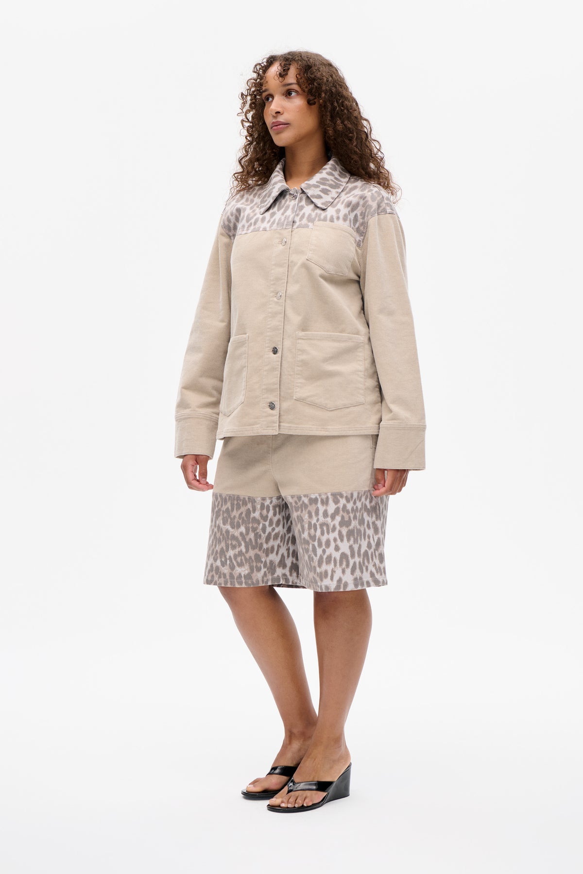 Model wearing a beige button-front jacket with an animal-print collar and shoulder yoke, paired with matching printed shorts.