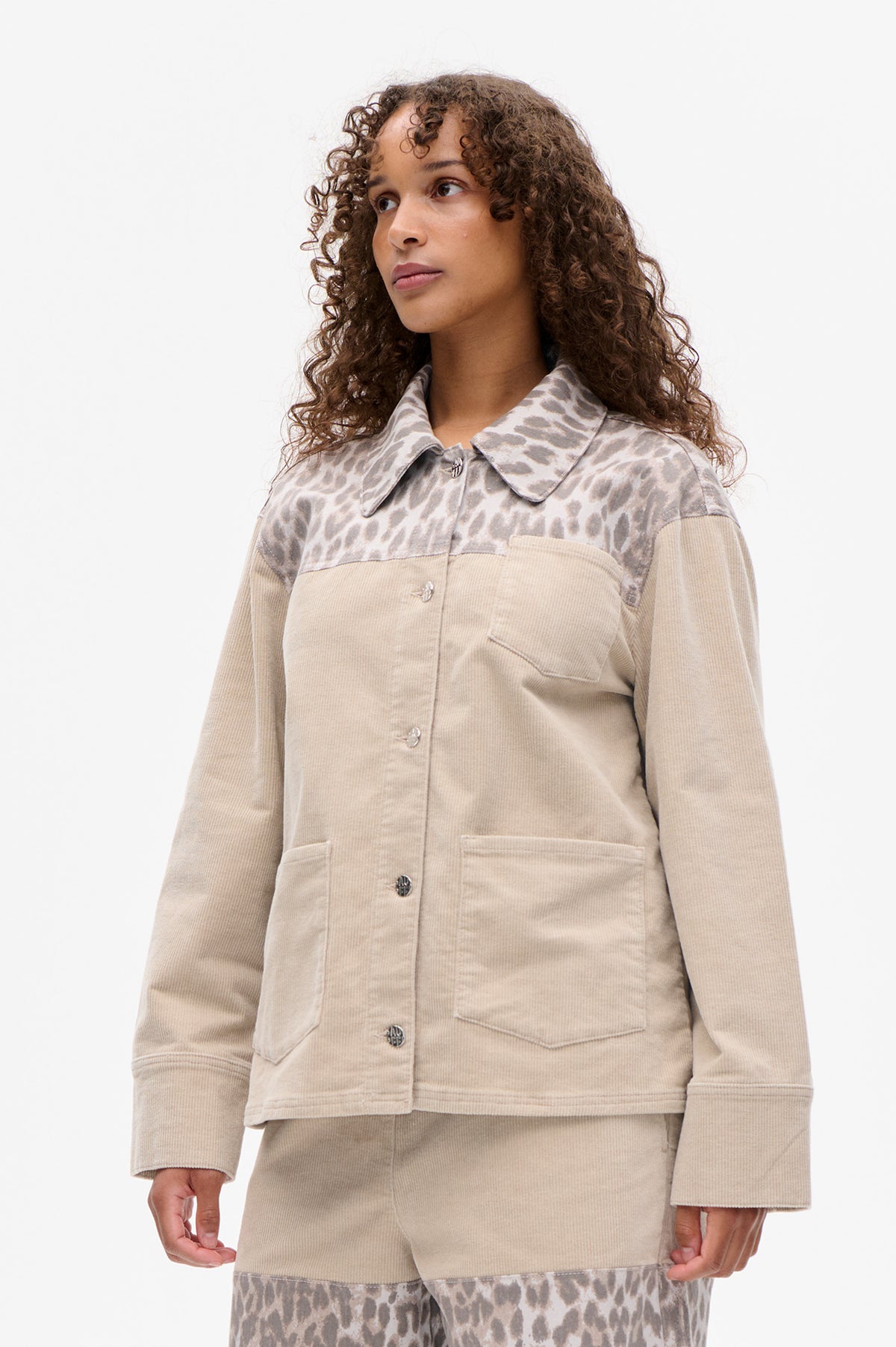 Front view of a beige corduroy jacket with a taupe abstract animal-print yoke and collar, metal buttons and patch pockets.