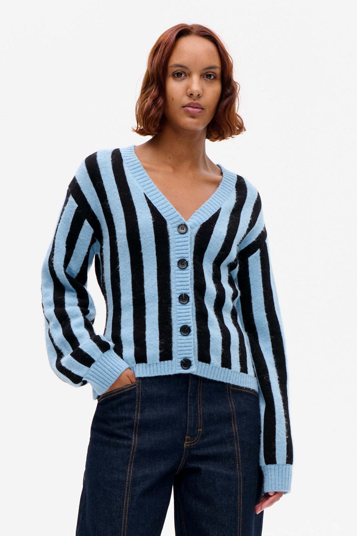Model wearing a light blue and black vertically striped button-front cardigan with a ribbed V-neck and cuffs, shown from the front.