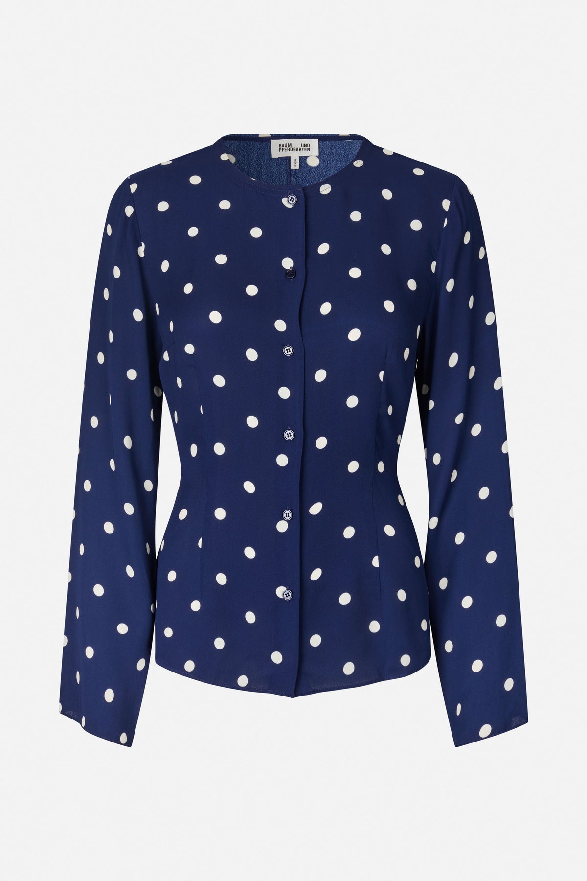 Front view of a navy long-sleeved button-front blouse with a round neckline and scattered white polka dots.