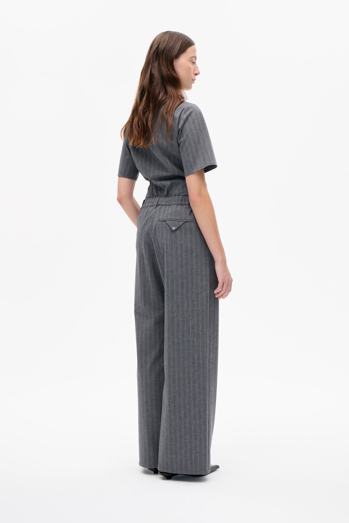 Seiten- und Rückansicht eines anthrazitgrauen Jumpsuits mit Nadelstreifen, kurzen Ärmeln, weiten Beinen und einer geknöpften Gesäßtasche.