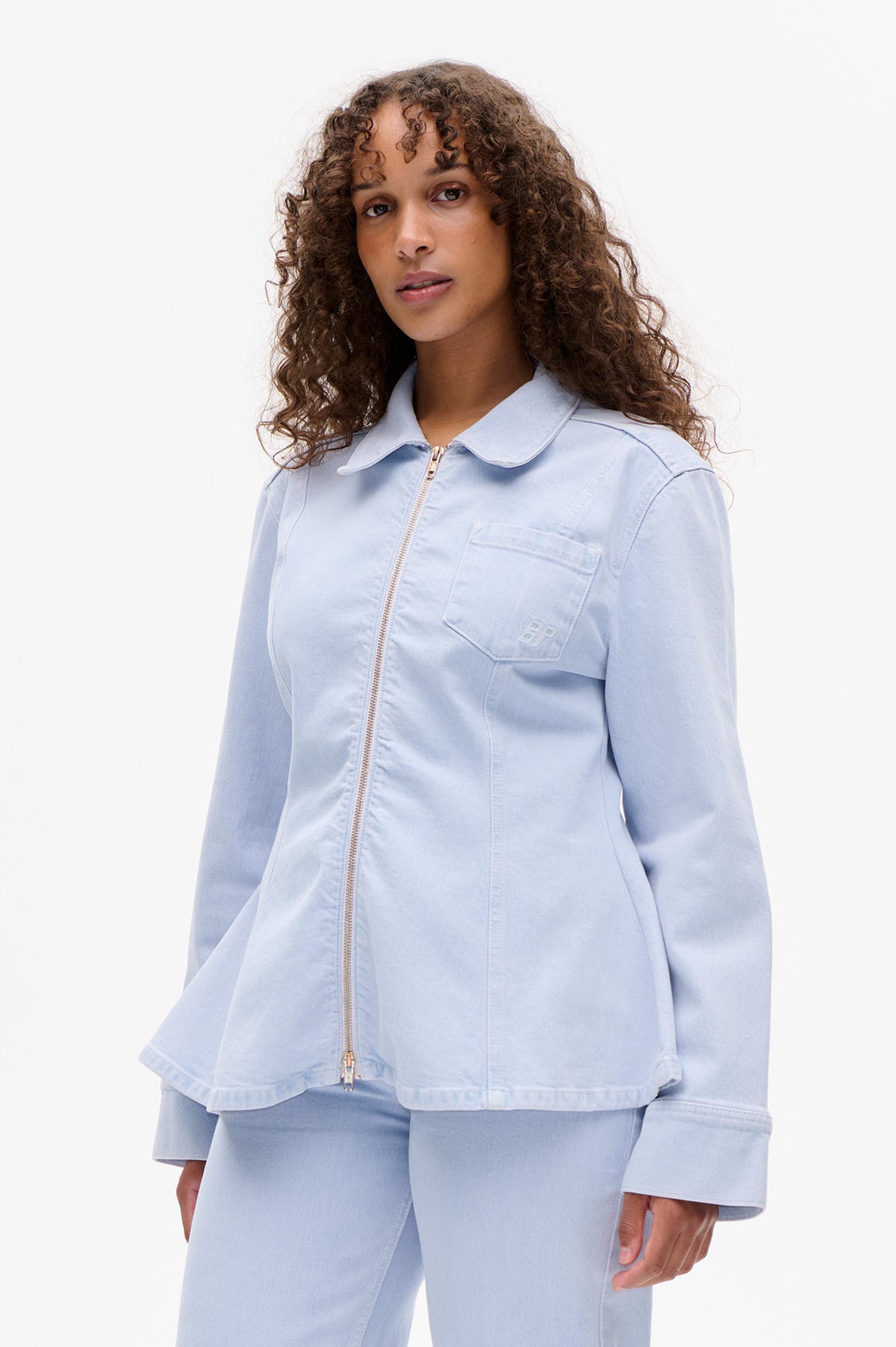 Front view of a pale blue zip-front jacket with an oversized collar and chest pocket, styled with matching trousers.