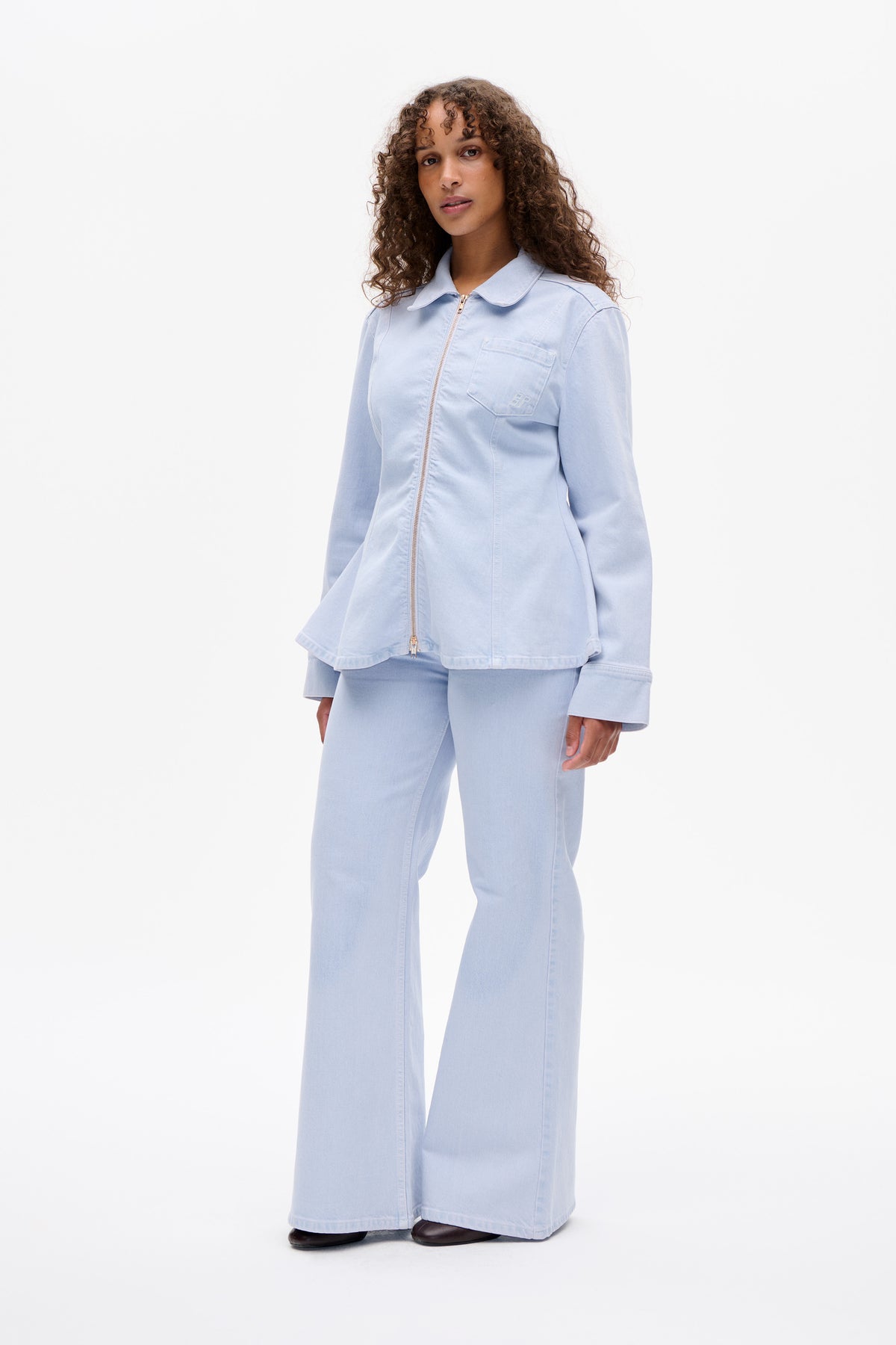 Model wearing a pale blue zip-front jacket with a chest pocket and matching wide-leg trousers, shown from the front.