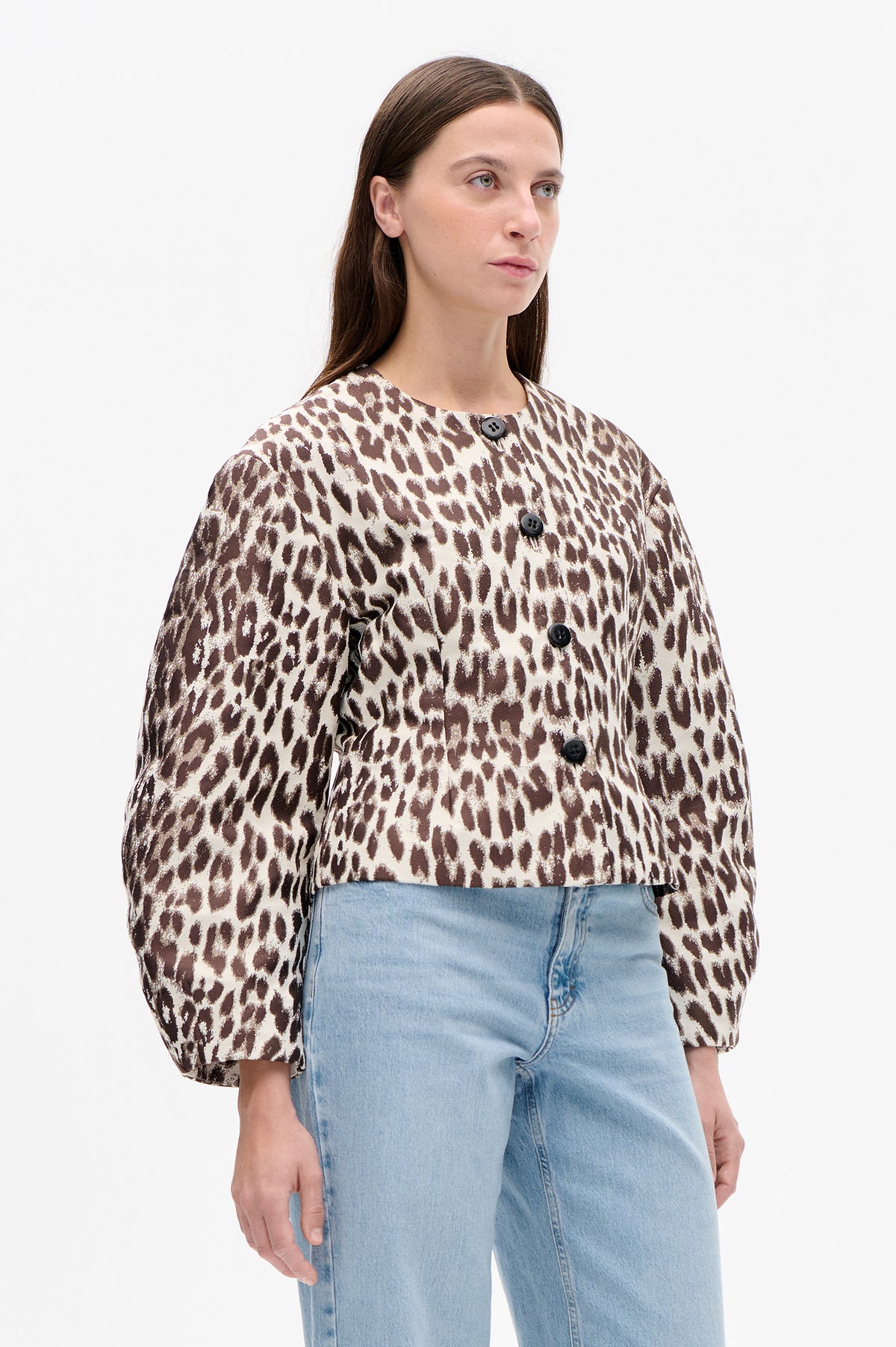 Front view of a cream and brown animal-print button-front jacket with a round neckline and long sleeves, worn with light-wash jeans.