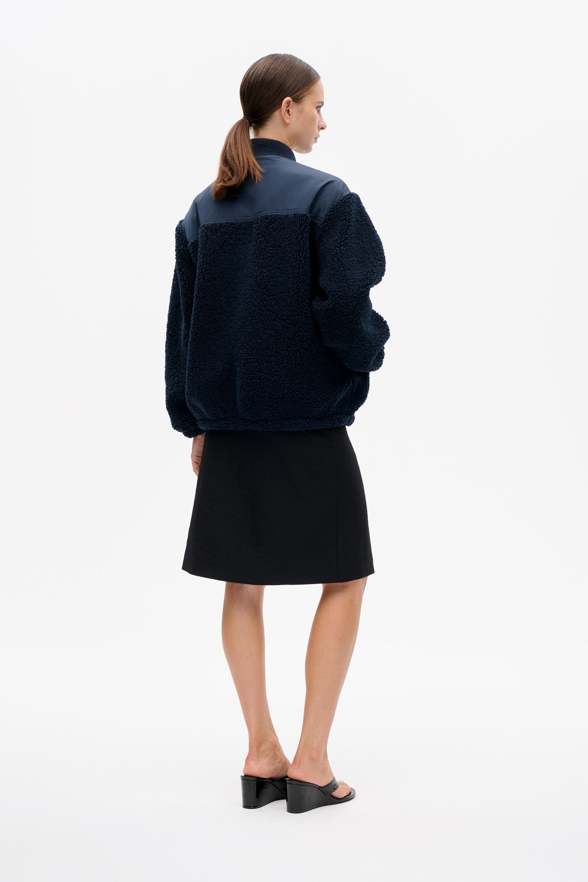 Model wearing a dark navy teddy fleece jacket with a smooth shoulder yoke, shown from the back and side.