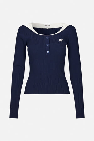 Front view of a navy ribbed long-sleeve top with a white contrast neckline, three front buttons and a small embroidered emblem.