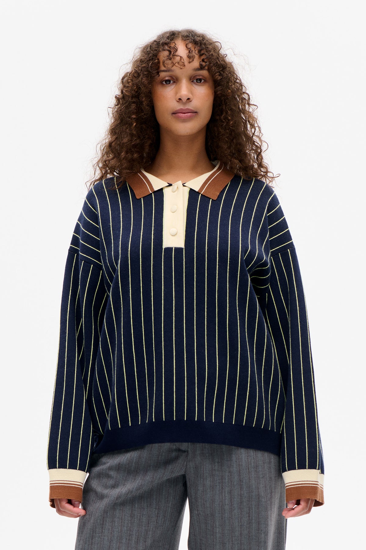 Front view of a navy long-sleeved knit polo with fine cream vertical stripes, a cream button placket, and brown-and-cream collar and cuffs.
