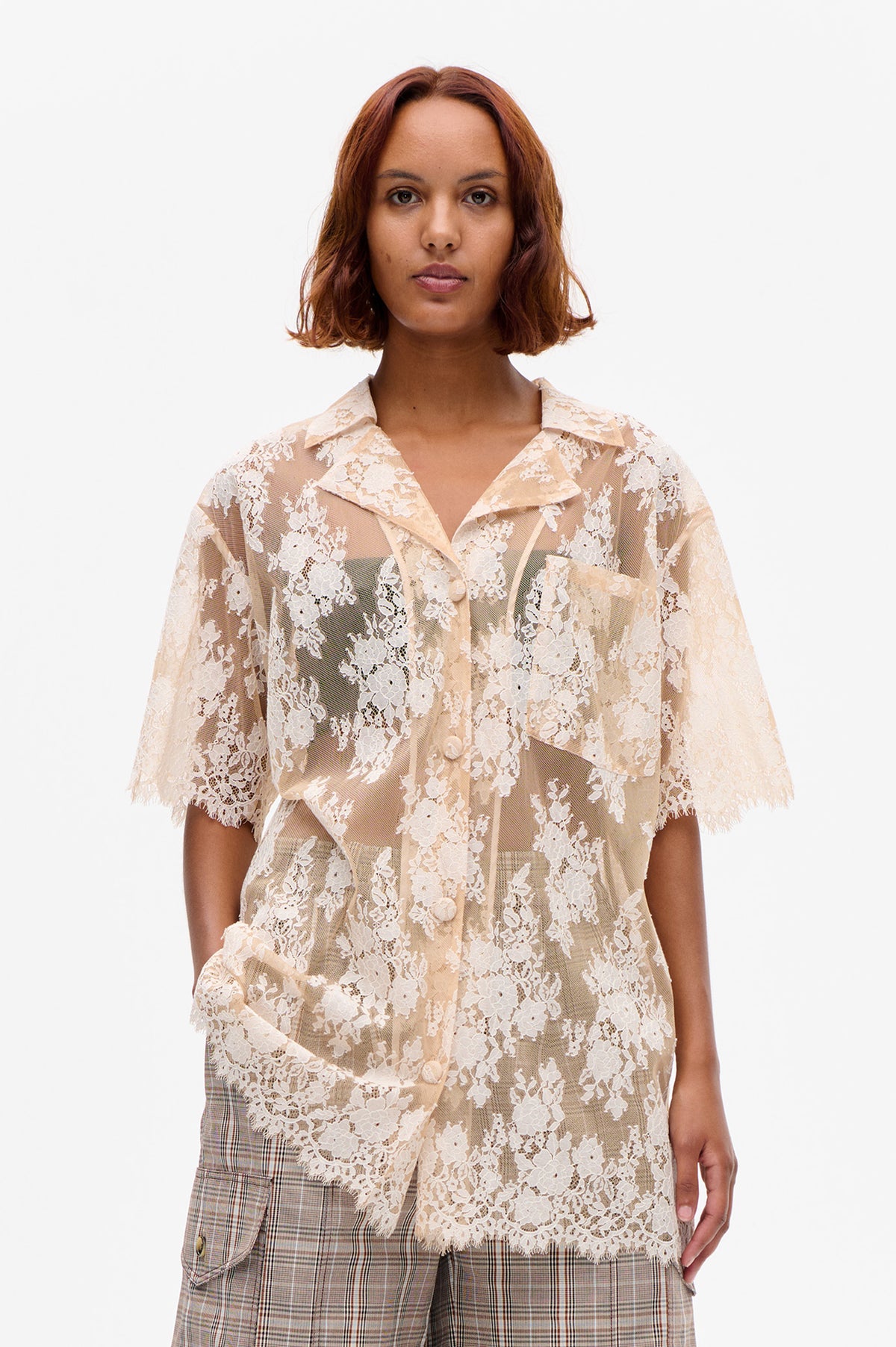 Front view of a sheer beige blouse with white floral lace, a wide collar, short sleeves and front buttons.