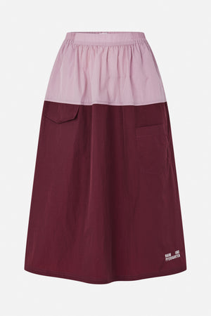Front view of a long two-tone skirt with a pale pink gathered waistband panel, burgundy A-line body, patch pockets and a small hem logo.