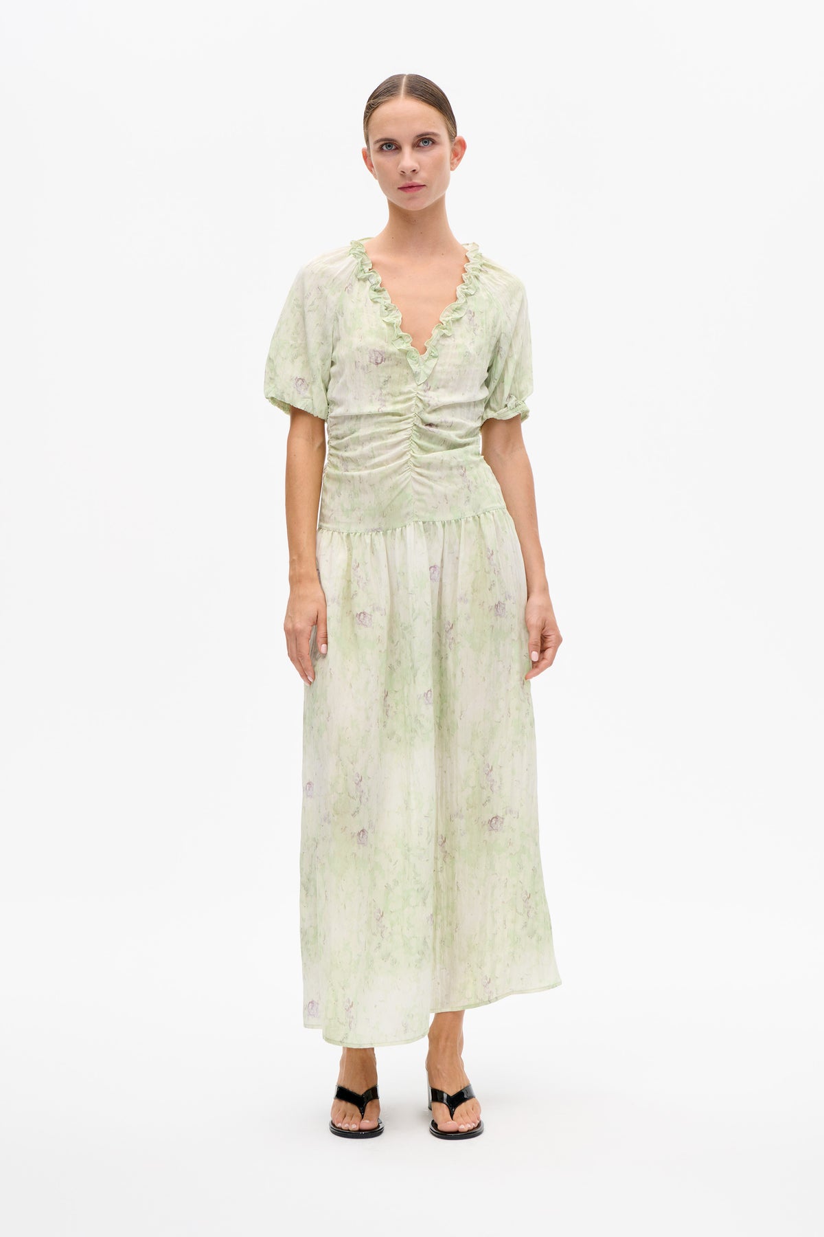 Front view of a model wearing a pale green floral-print midi dress with a ruffled V-neck, puff sleeves and a gathered waist.