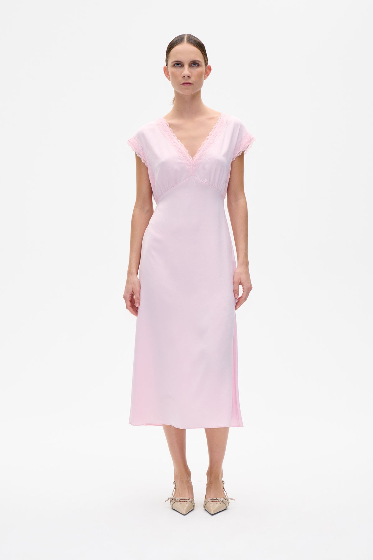 Front view of a pale pink knee-length dress with a V-neck, lace-trimmed cap sleeves and neckline.