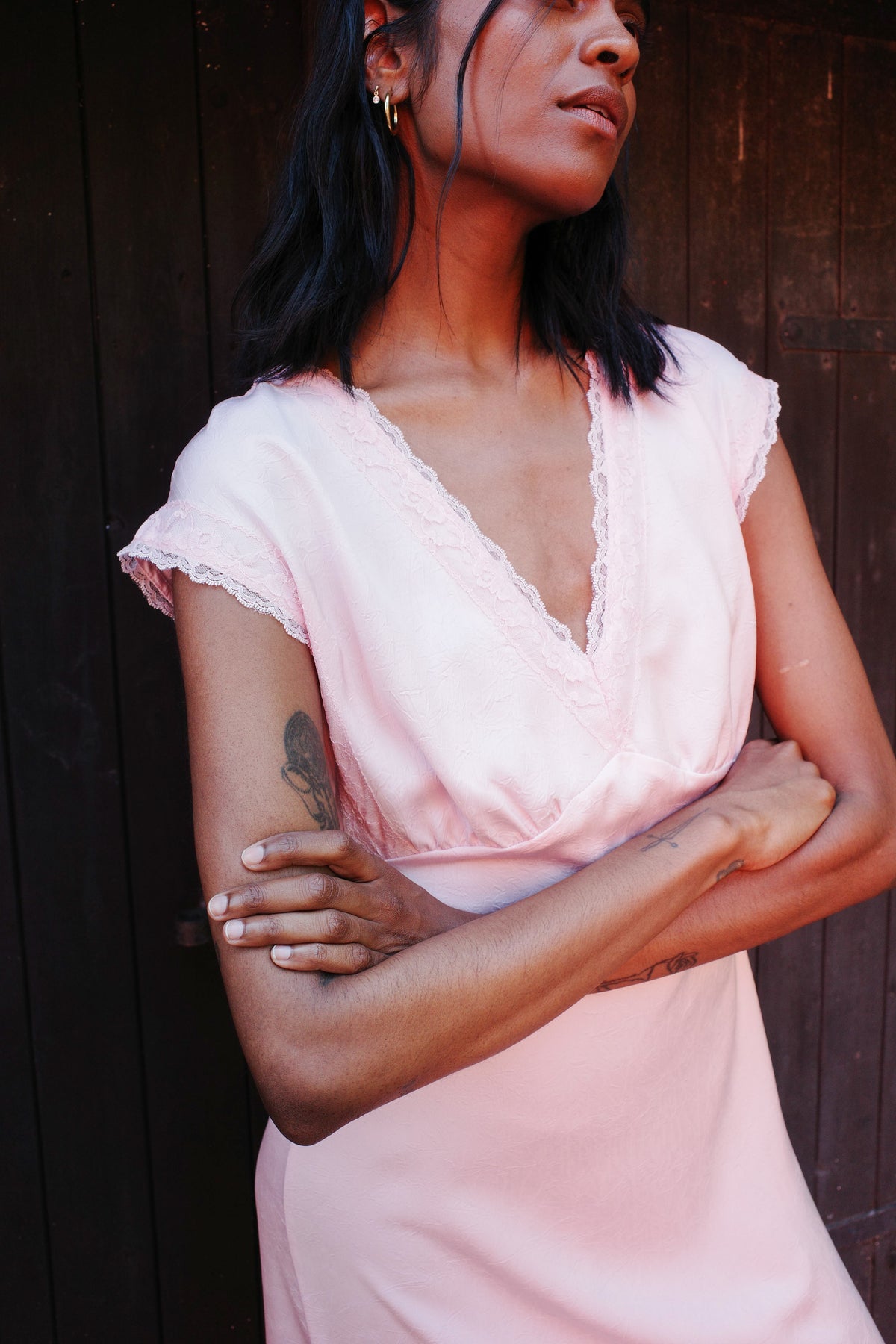 Close-up campagneportret van een model dat een lichtroze blouse draagt met een diepe V-hals en een geschulpte kantenrand.