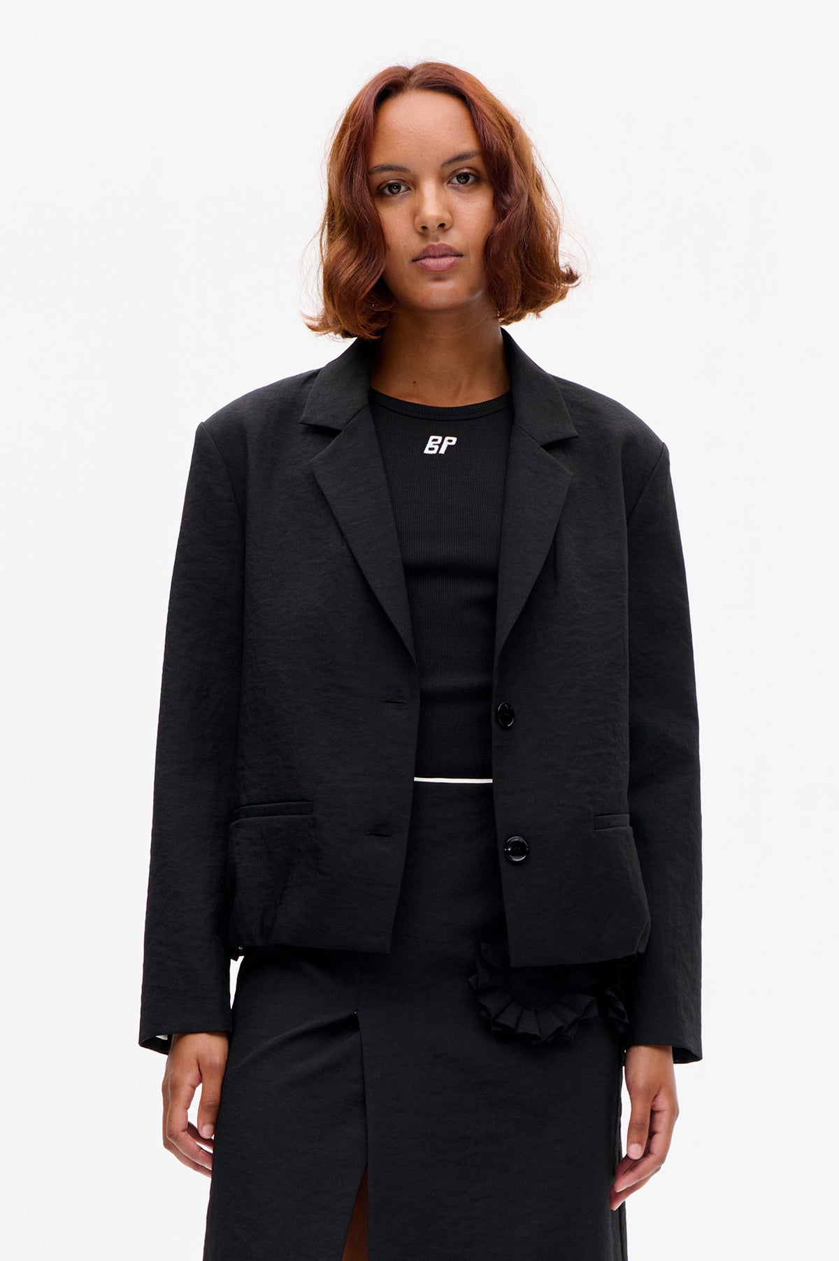 Front view of a model wearing a dark charcoal tailored blazer over a black ribbed top with a small white BP logo.