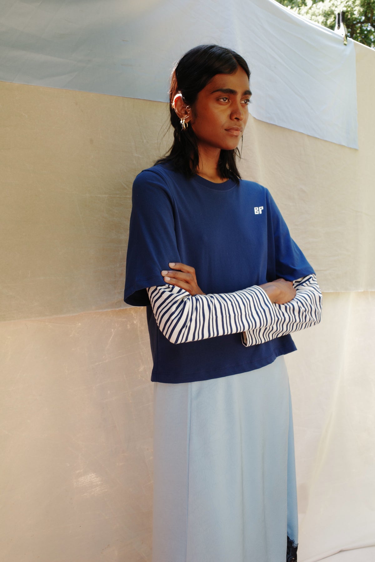 Campaign portrait of a model wearing a navy T-shirt with a small white BP logo over a white top with navy wavy stripes