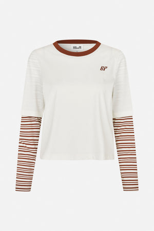Front view of an ivory short-sleeve T-shirt layered over a rust-brown and ivory striped long-sleeve top, with a contrasting neckline and chest monogram.