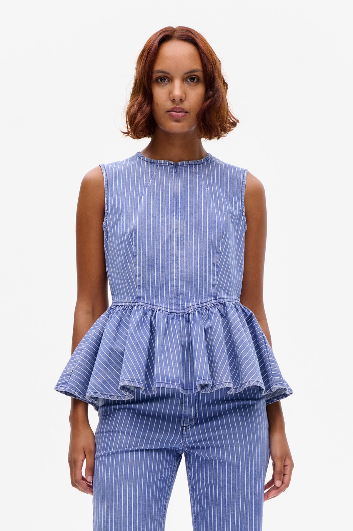 Front view of a blue-and-white pinstripe sleeveless top with a gathered peplum layer and matching trousers