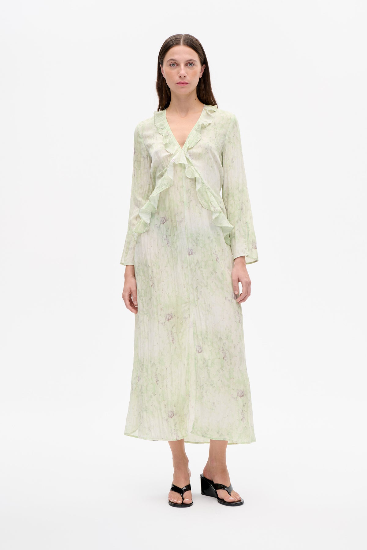 Front view of a long-sleeved midi dress with a pale green and muted purple abstract print, deep V-neck and cascading ruffles.