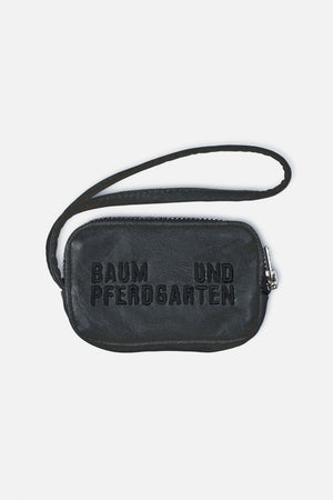 Black pebbled crossbody bag with a long strap, silver-tone zipper and raised Baum und Pferdgarten lettering on the front.