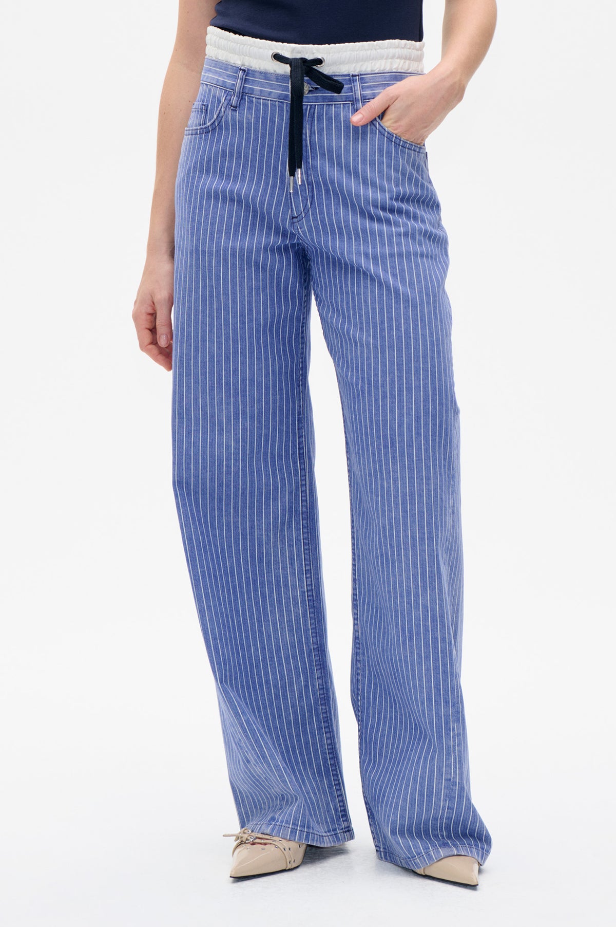 Frontdetail einer blauen Nadelstreifenhose mit weißem elastischem Bund, schwarzem Kordelzug und Vordertaschen.
