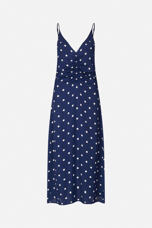 Front view of a navy slip dress with cream polka dots, thin adjustable straps, a V-neck and ruched button detail down the centre.