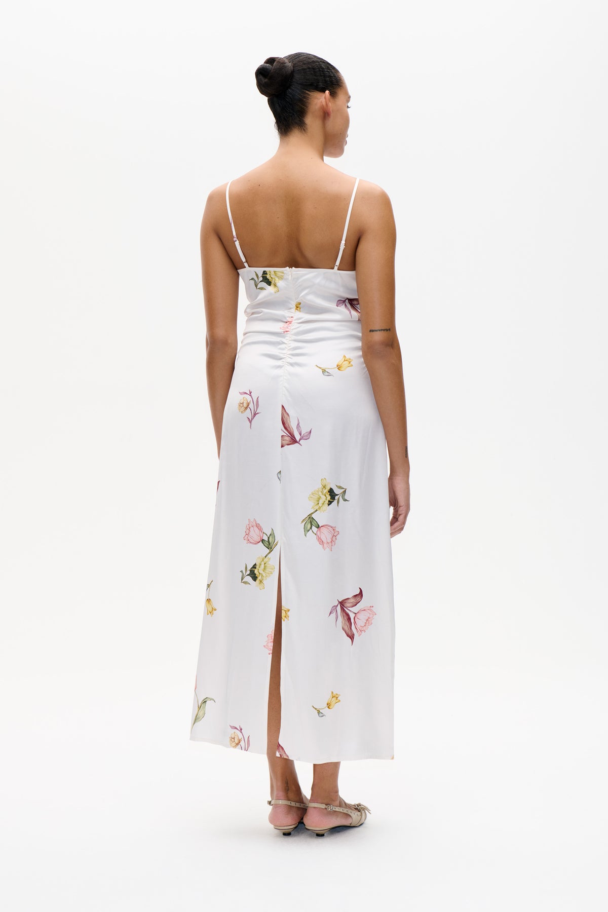 Back view of a white spaghetti-strap midi dress with a colourful floral print, back zip and thigh-high side slit.
