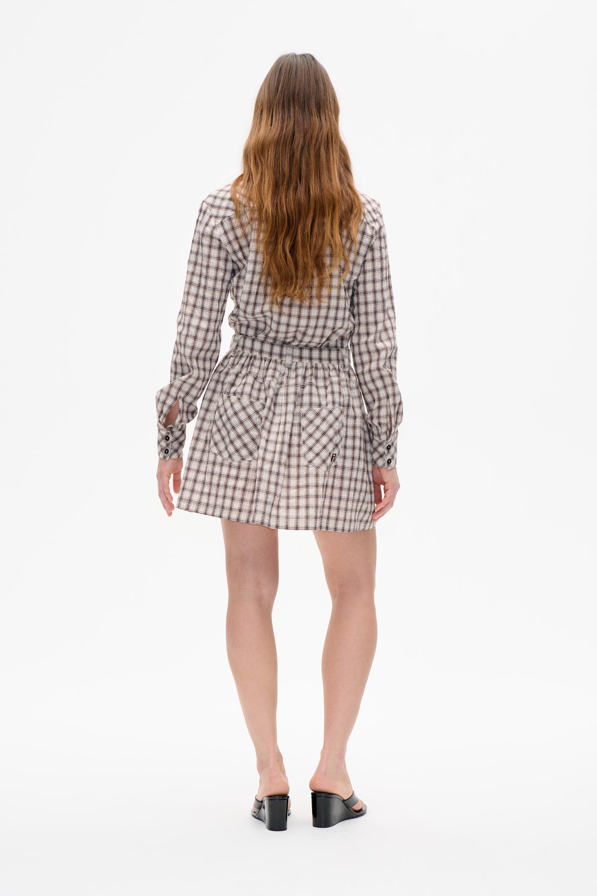 Back view of a long-sleeved, belted shirt dress in a cream and dark plaid, with a gathered skirt.