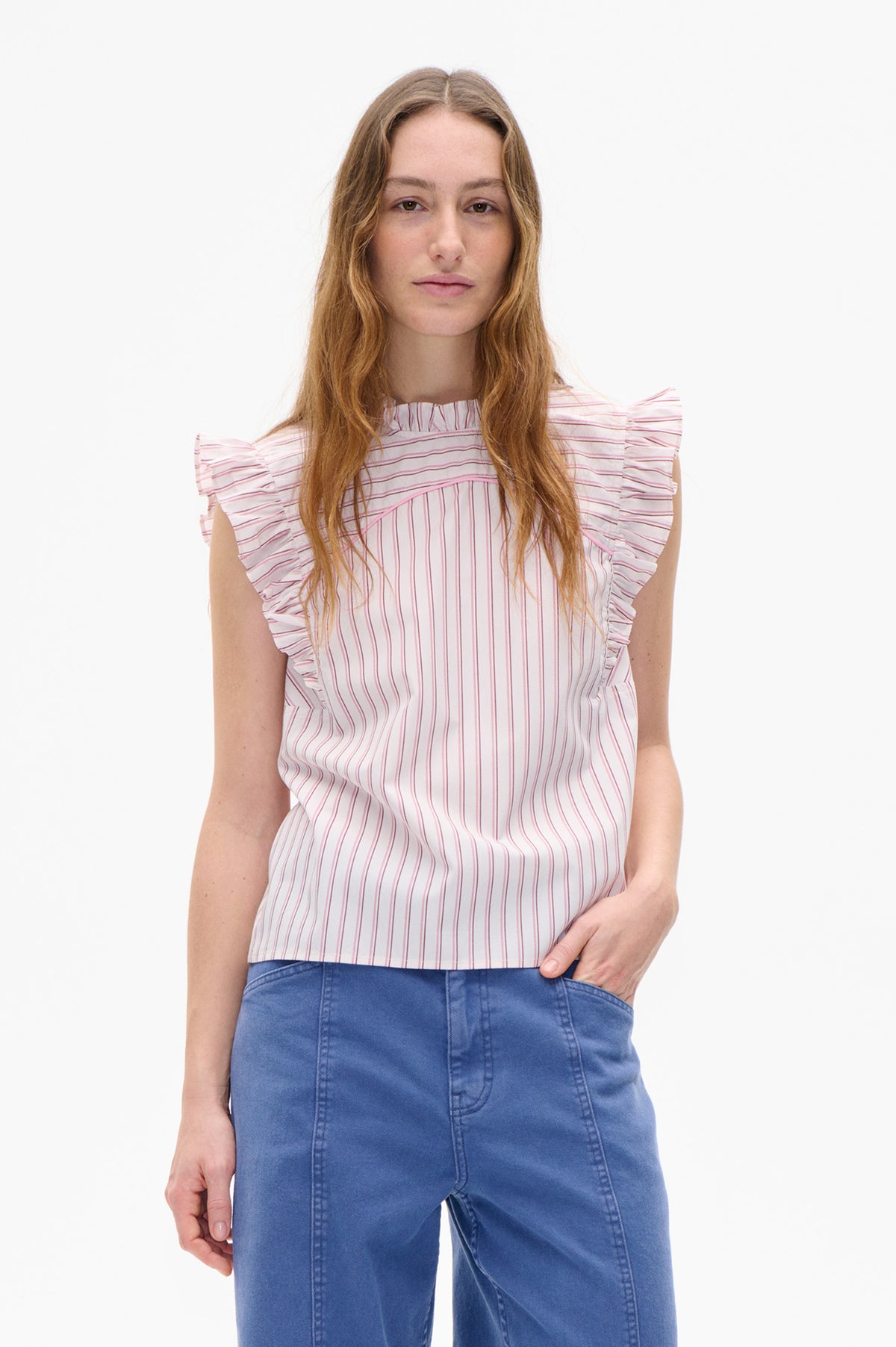 Front view of a white blouse with fine pink and gray stripes, a gathered high neckline, and layered ruffle cap sleeves, paired with blue jeans.