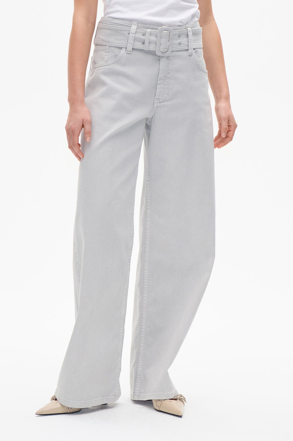Front detail of pale grey wide-leg jeans with a matching wide belt and oversized buckle, styled with a white top.