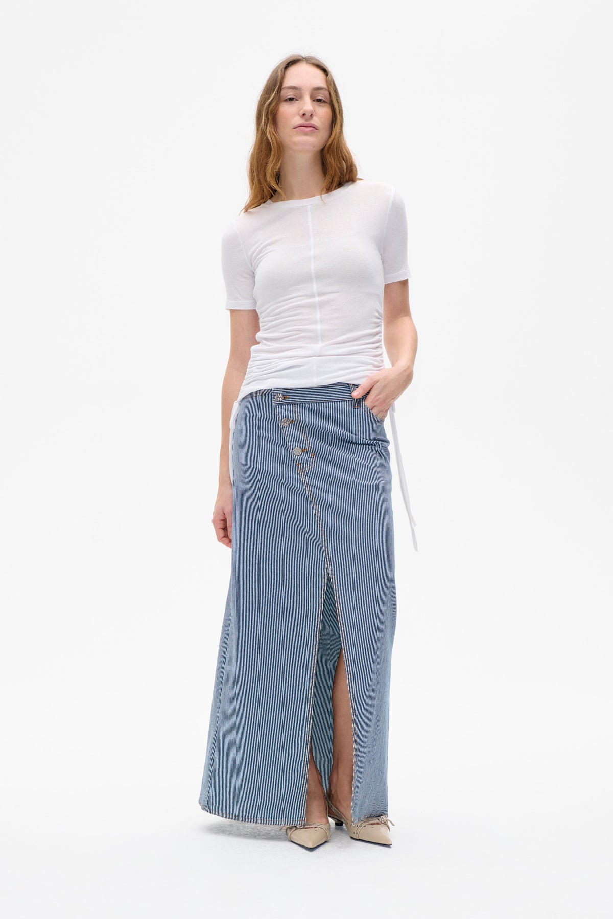 Model wearing a white short-sleeve top with a center seam and a blue-and-white pinstriped long skirt with a front slit.