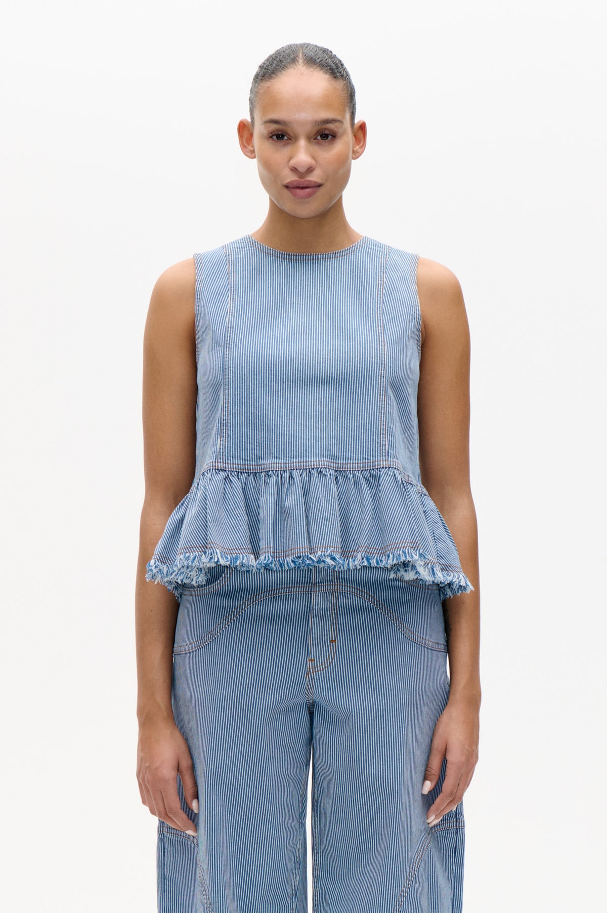 Front view of a blue-and-white pinstriped sleeveless top with a gathered, frayed peplum and matching trousers.
