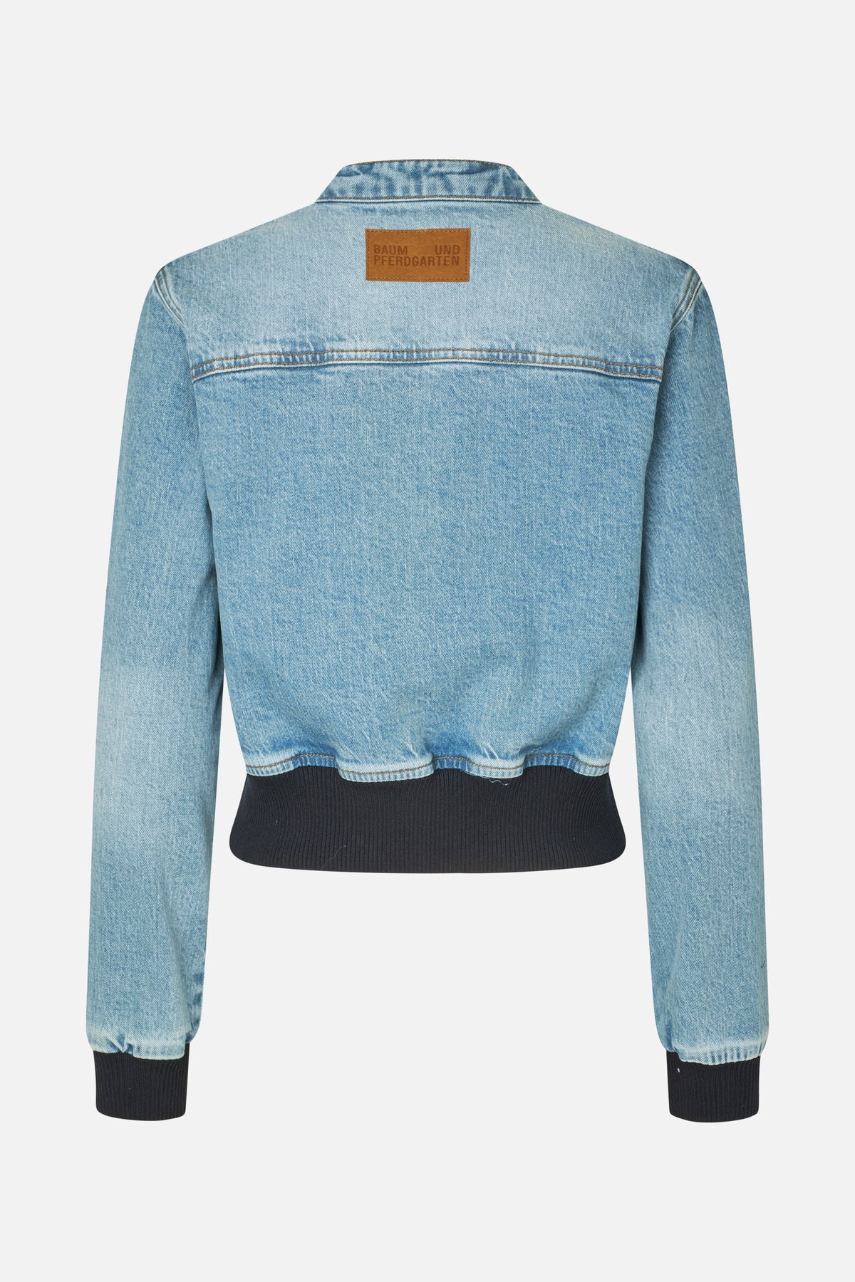 Back view of a light blue denim jacket with a brown leather-look patch, stitched yoke and black ribbed hem and cuffs.