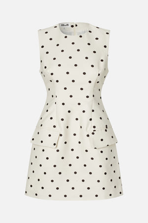 Front view of a sleeveless cream dress with black polka dots, a round neckline, fitted waist and flared skirt with flap pockets.