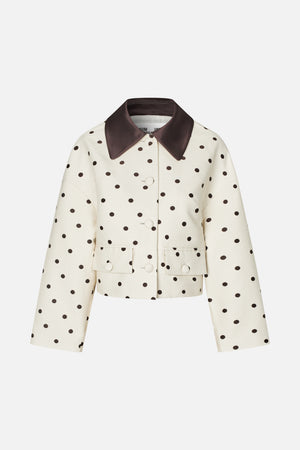 Front view of a cropped cream jacket with dark brown polka dots, a wide contrasting collar, button fastening and flap pockets.