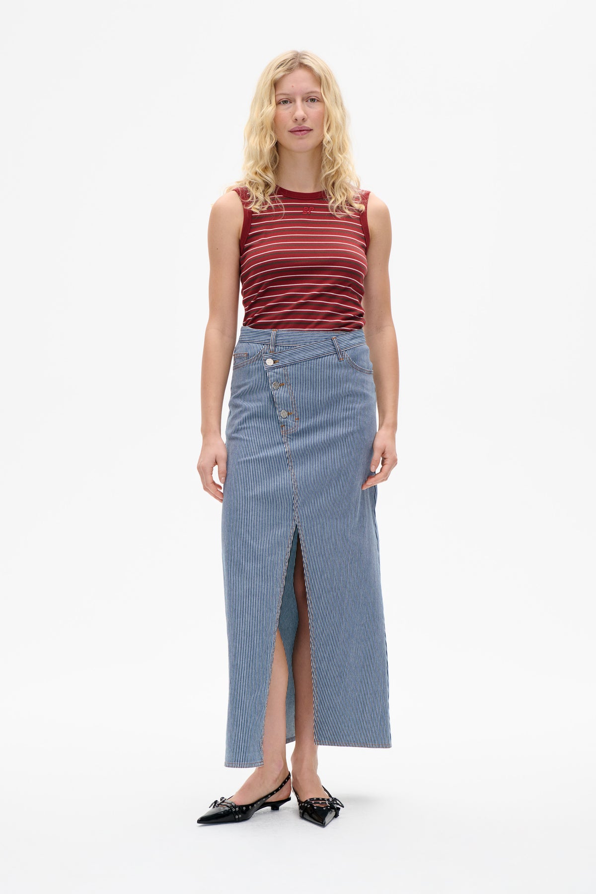 Front view of a burgundy sleeveless top with thin horizontal stripes, paired with a blue-and-white vertically striped denim midi skirt with a front slit.