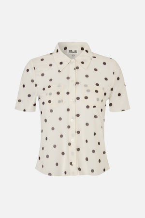 Vooraanzicht van een ivoorkleurige blouse met korte mouwen, knoopsluiting, donkere stippen, een puntskraag en twee borstzakken.