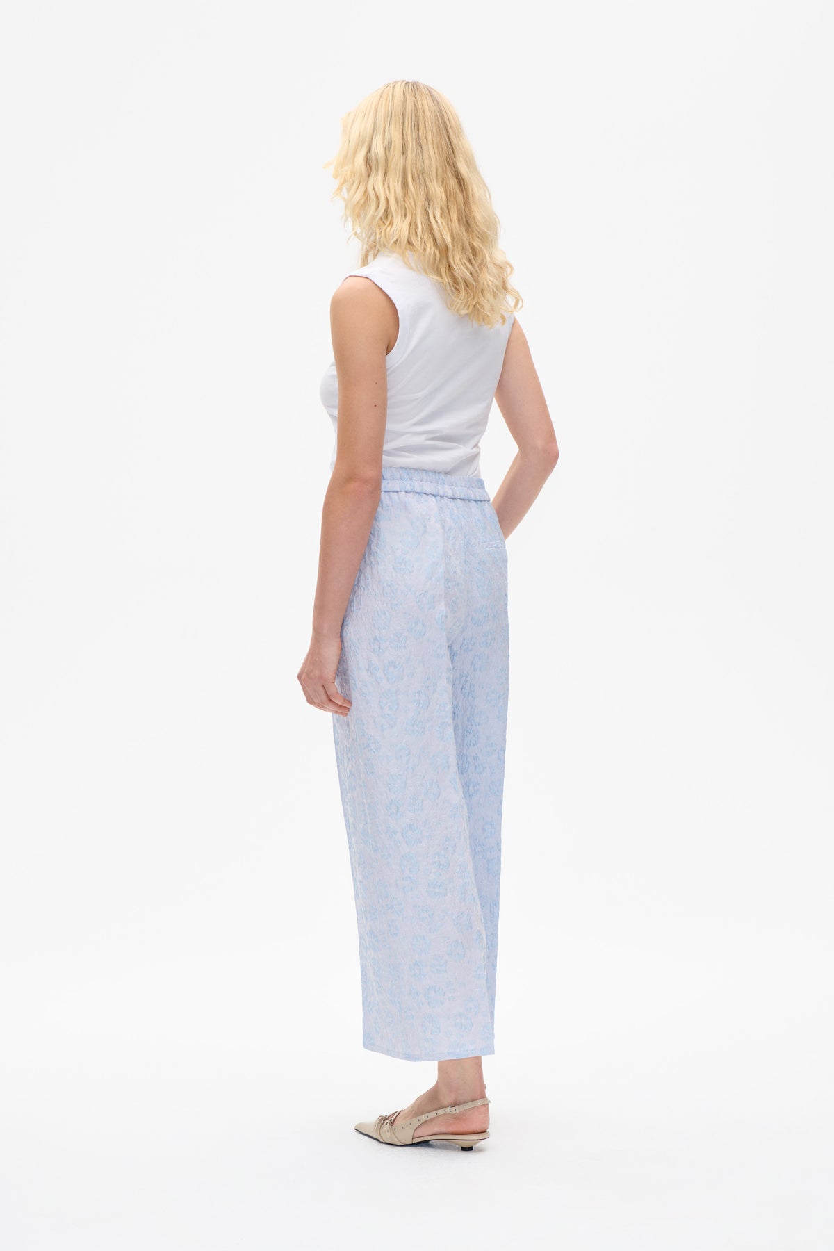 Back view of a model wearing a white sleeveless top and a light blue floral midi skirt with a gathered waistband.