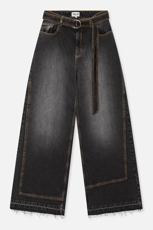 Front view of charcoal-black wide-leg jeans with orange contrast stitching, a circular metal belt buckle, rectangular leg panels and frayed hems.