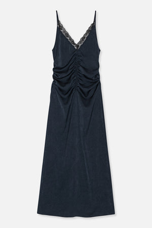 Front view of a long dark navy slip dress with thin straps, a lace-trimmed V-neck and ruching down the centre front.