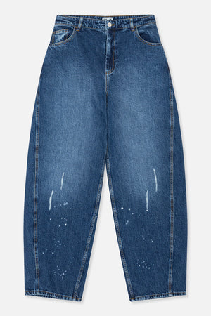Vooraanzicht van wijdvallende blauwe jeans met contrasterende oranje stiksels, gebogen zakken en verspreide witte spetters op de broekspijpen.