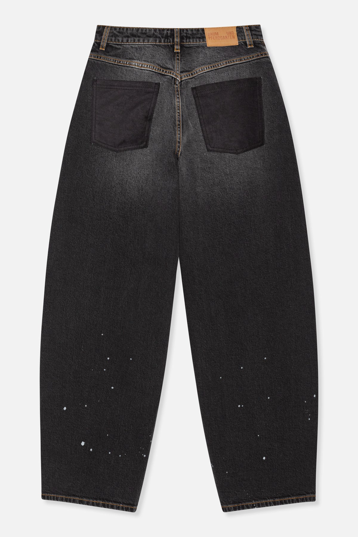 Achteraanzicht van antracietzwarte jeans met contrasterende bruine stiksels, grote donkere opgestikte zakken en verspreide witte spikkels op de pijpen.