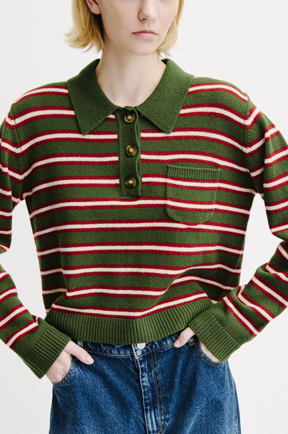 Front view of a green knitted button-front sweater with a collar and horizontal red and cream stripes, worn with blue jeans.