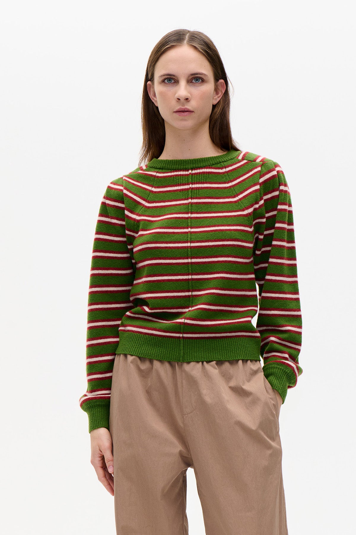 Front view of a green crew-neck sweater with red and white horizontal stripes, worn with taupe trousers.