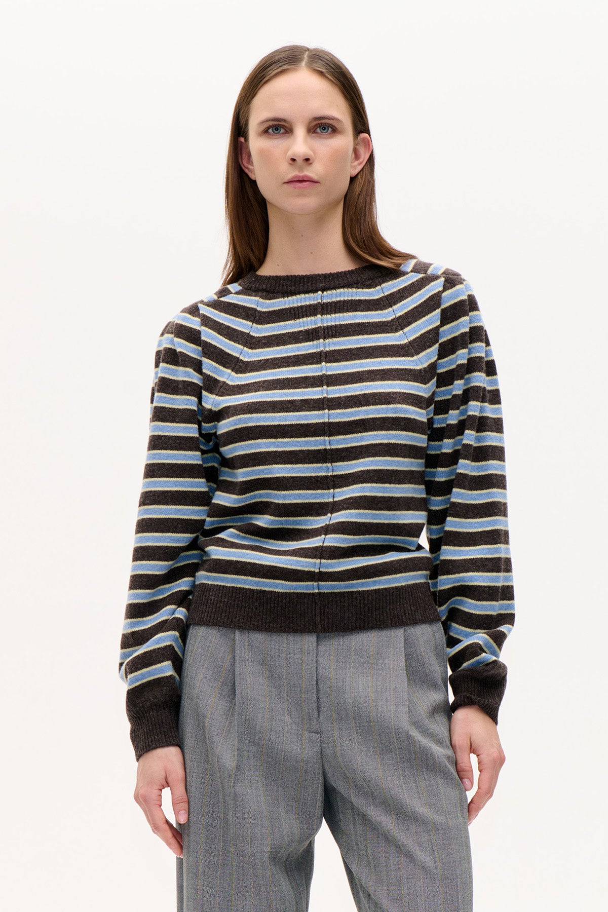 Front view of a dark brown crew-neck sweater with horizontal blue and pale yellow stripes, styled with grey pinstriped trousers.