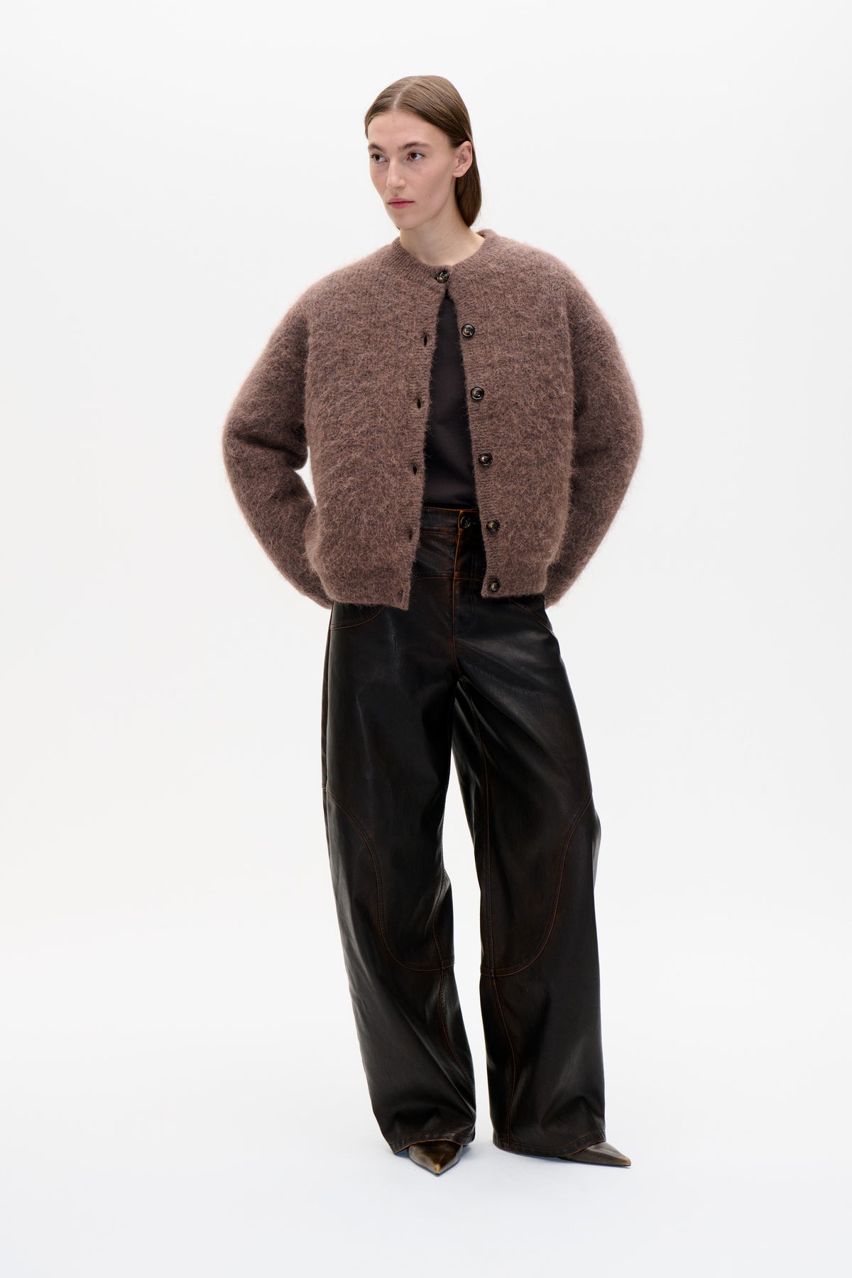 Front view of a model wearing a fuzzy mauve-brown button-front cardigan with a round neck and black wide-leg trousers.