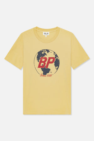 Front view of a pale yellow crew-neck T-shirt with a globe graphic, red “BP” lettering and “Since 1999” text.