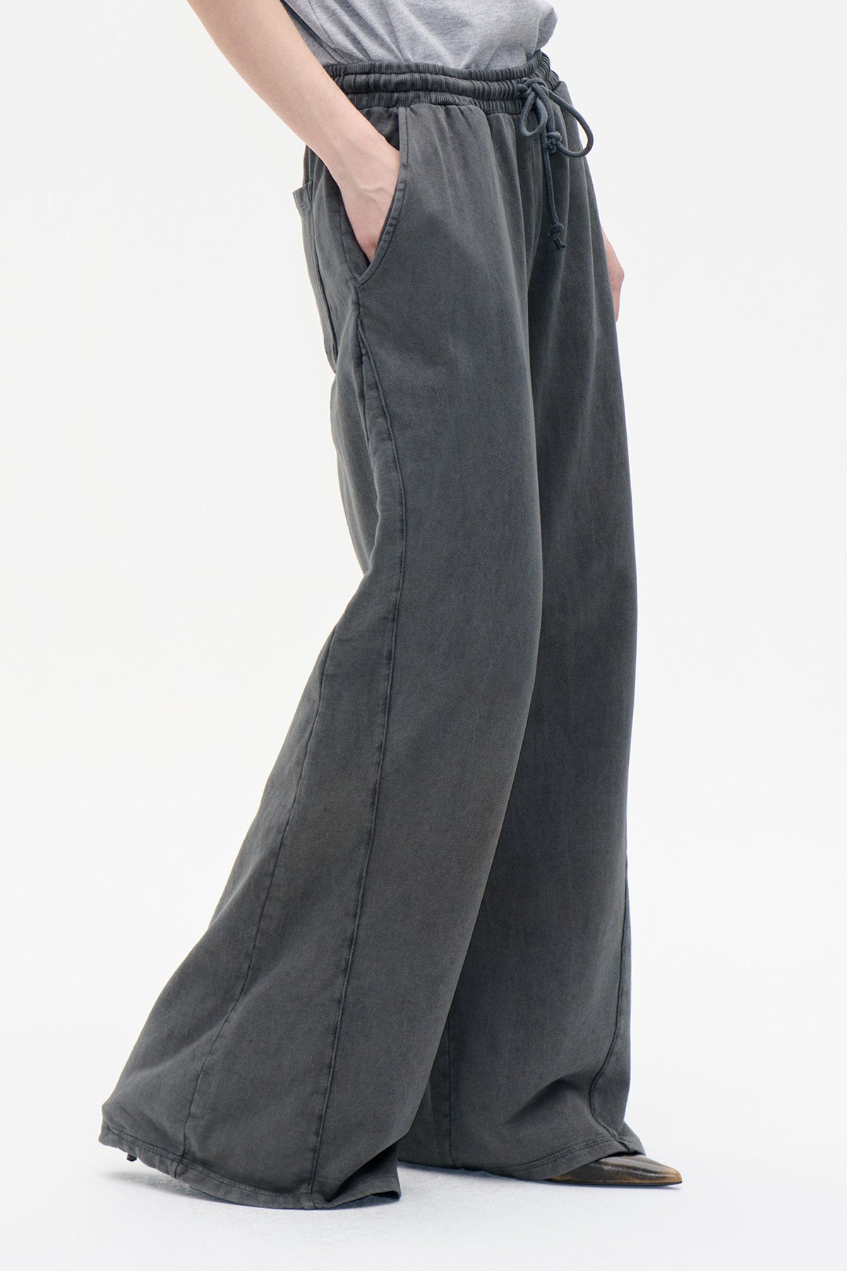 Close-up of charcoal washed wide-leg trousers with an elastic drawstring waist and side pockets.