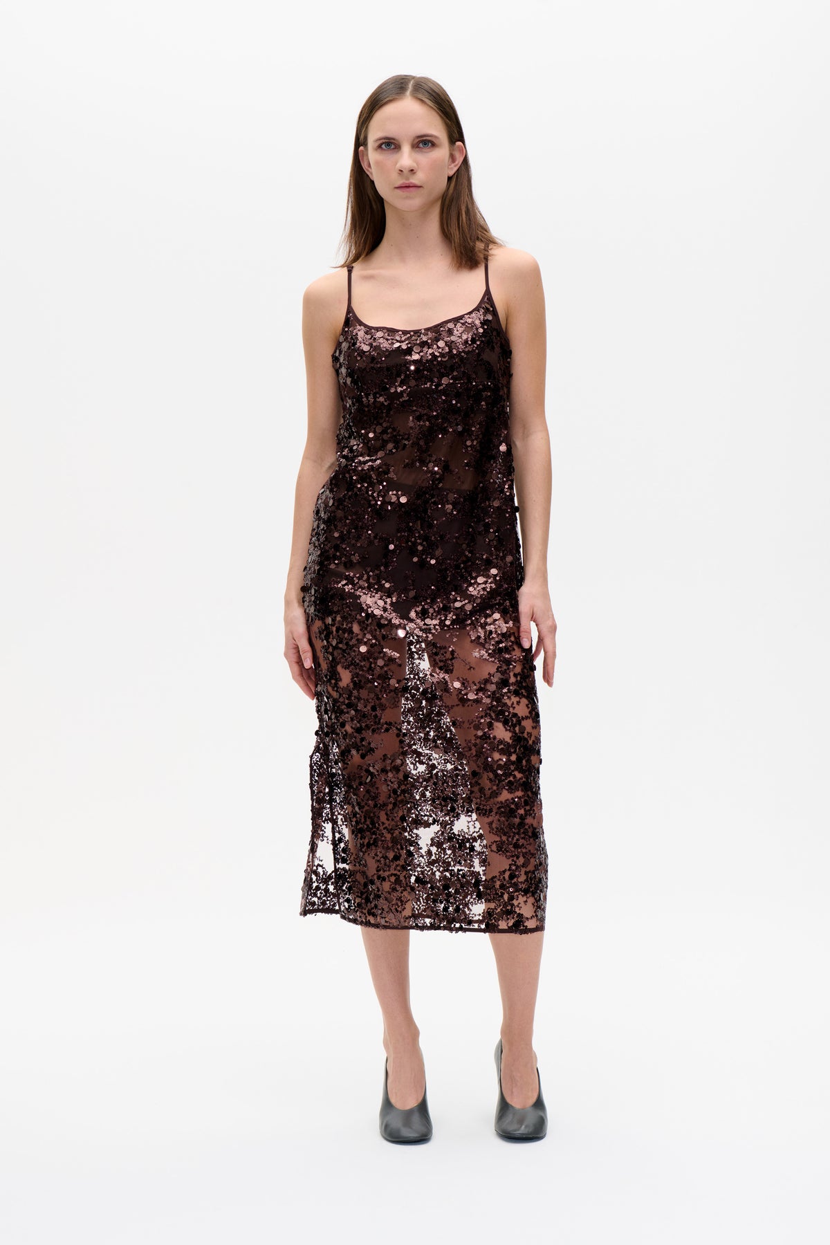 Front view of a model wearing a dark sheer slip dress with thin straps and dense mauve and black sequins.