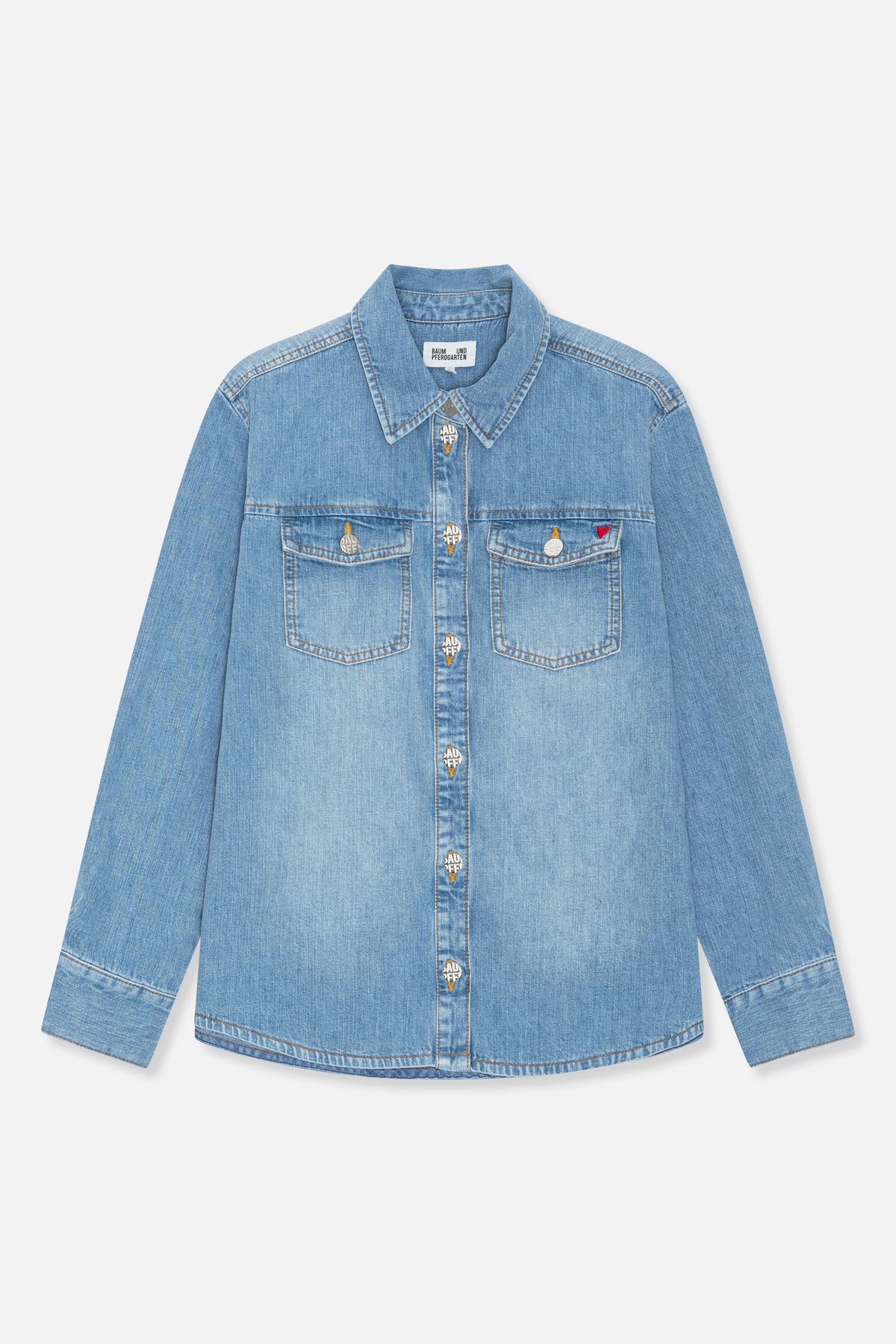 Front view of a light blue denim shirt with two chest pockets, branded buttons and a small red heart detail.