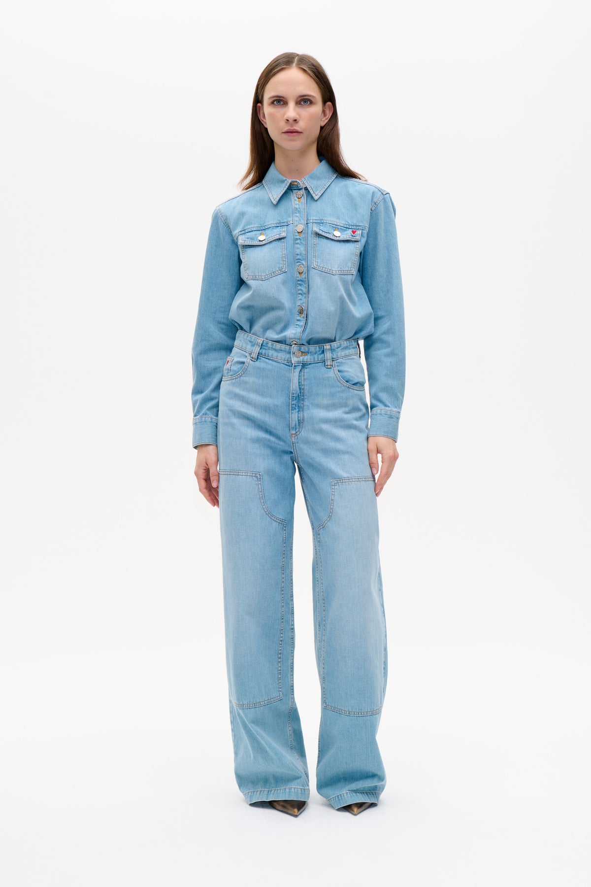 Model wearing a light blue denim button-up shirt with chest pockets and wide-leg jeans, shown from the front.