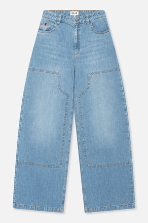 Vooraanzicht van lichtgewassen blauwe jeans met wijdvallende pijpen, extra grote rechthoekige zakken op de pijpen, contrasterend stiksel en een klein rood hartdetail.